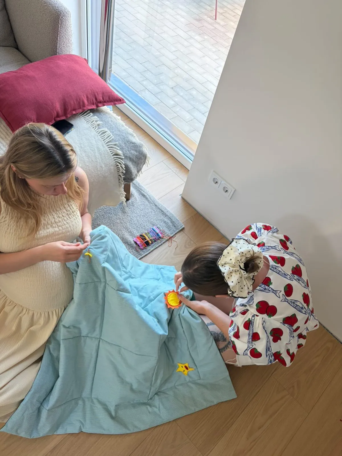 Two friends sewing a felt play mat together