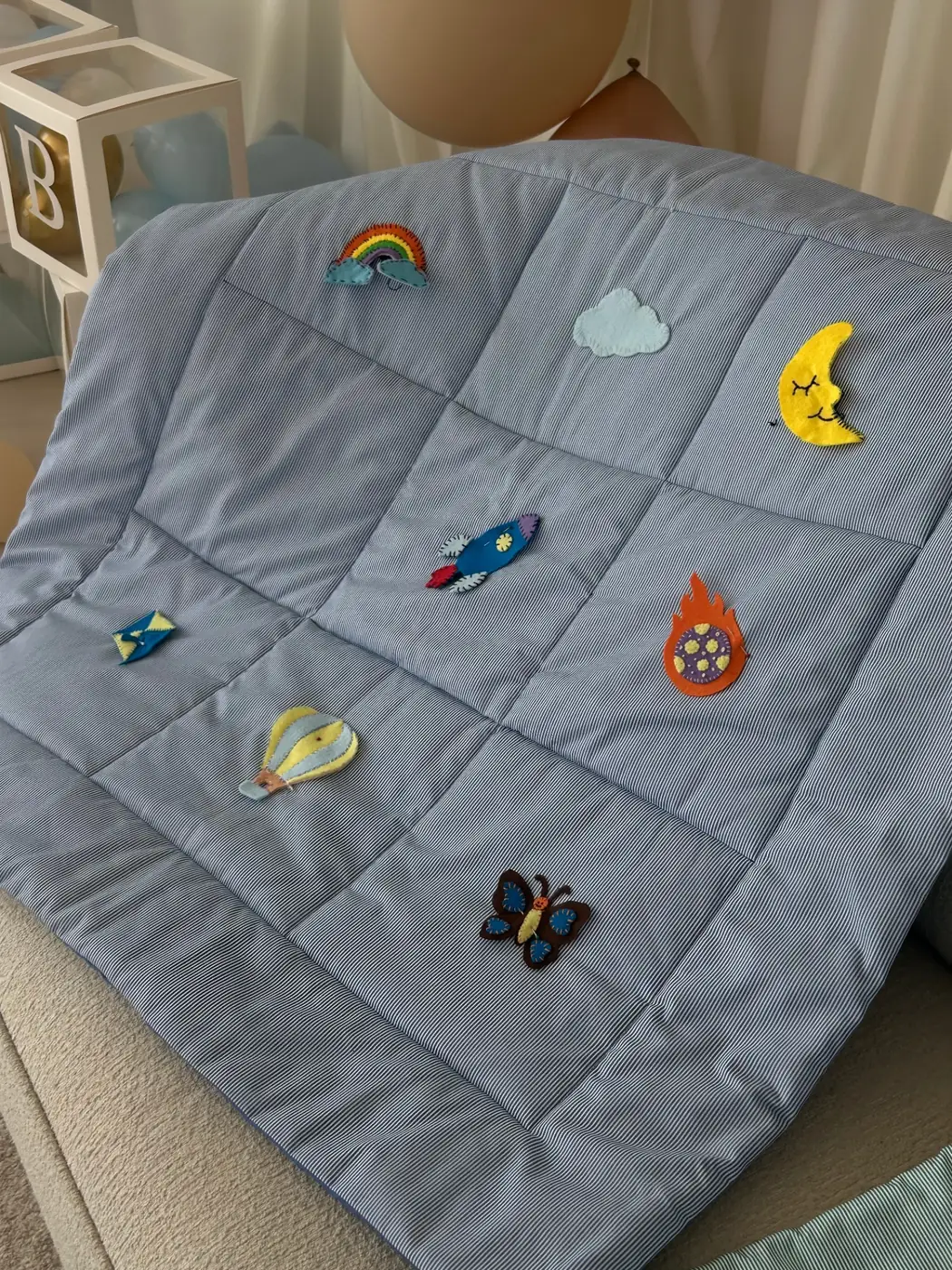 Blue play mat with rainbow, moon and rocket appliqués